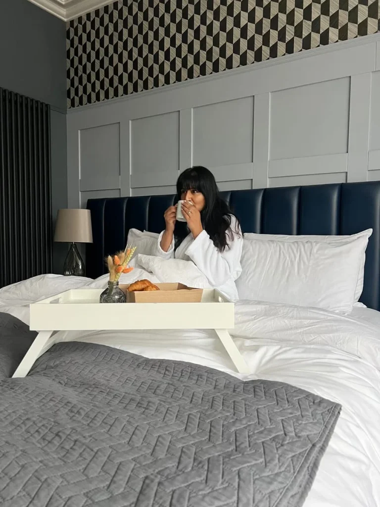 Bejal drinking tea in bed of Superior Room at St Martins Lodge, Leicester