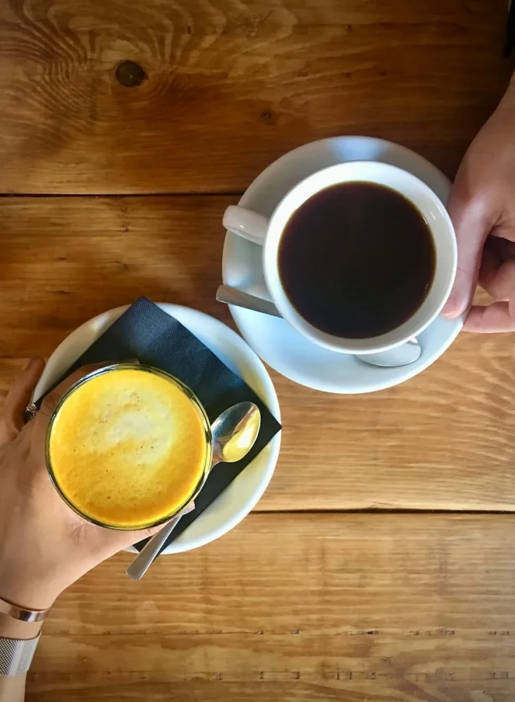 Turneric latte and black coffee top lay at Kai, Leicester on a wooden table background