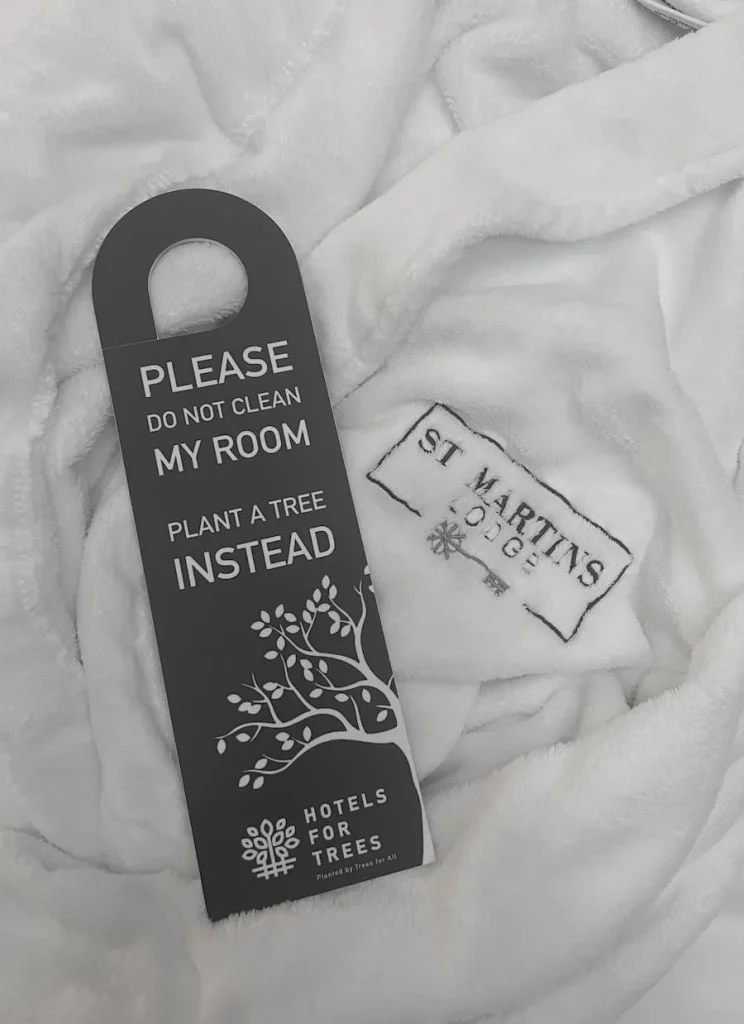 Plant a tree for hotels door sign on bed at St Martins Lodge, Leicester