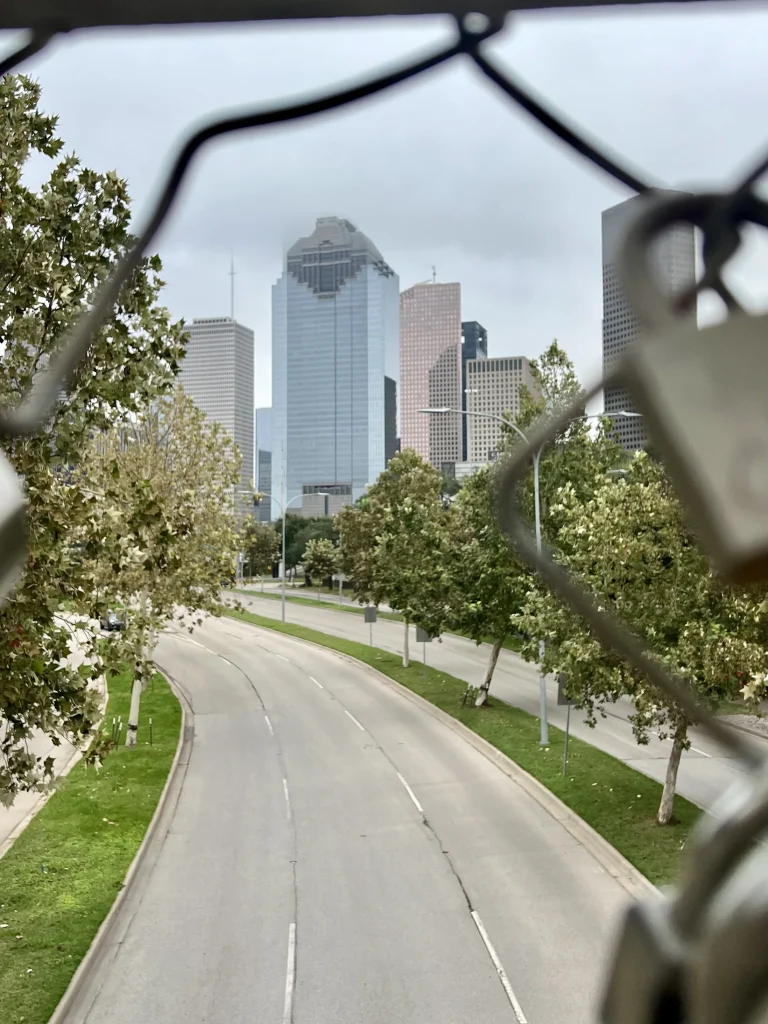Photo locations in Houston: Love Lock Bridge with downtown skyline through the wire fence surrounded in love locks.