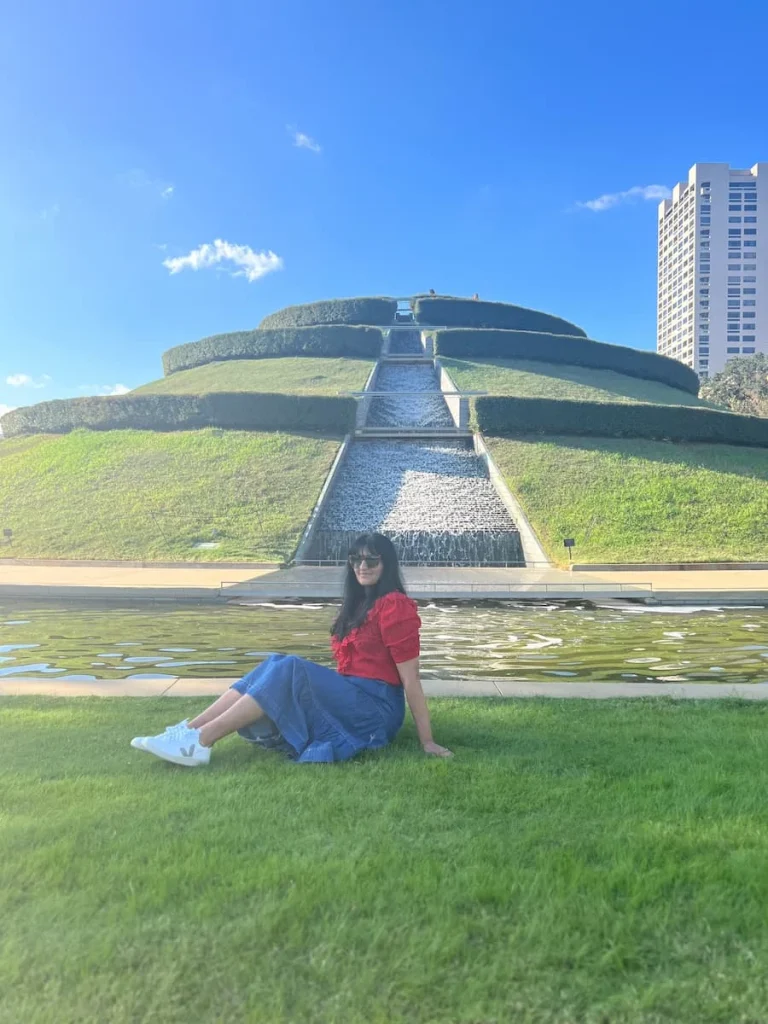 Photo locations in Houston: Bejal sitting on grass near the mound and water feature in McGovern Centennial Gardens