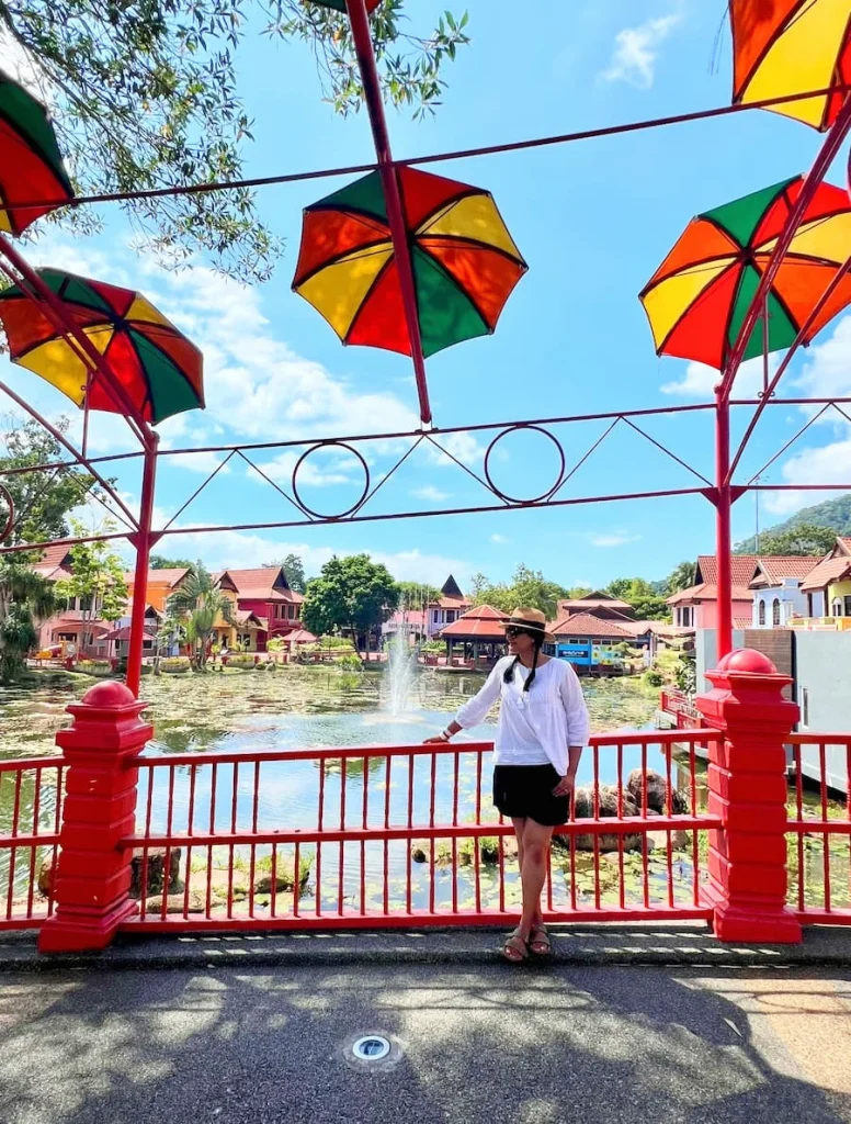Things to do in Langkawi: Bejal standing on Umbrella topped red bridge at Oriental Village