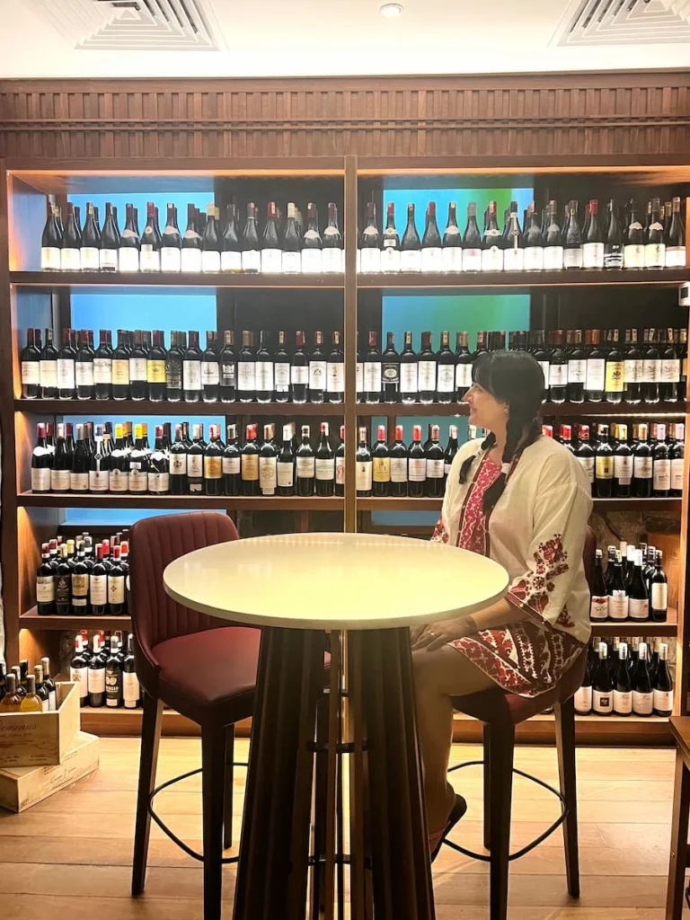 Bejal sitting inside the wine cellar at The Datai Langkawi with wine bottles on shelves in the background