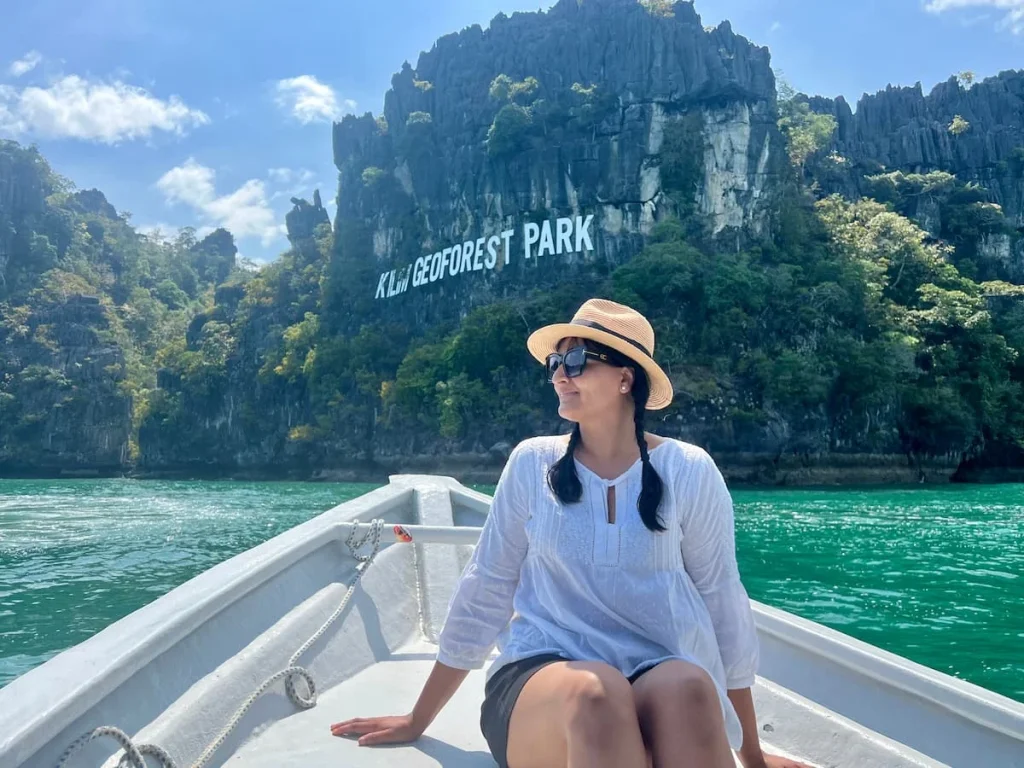 Things to do in Langkawi:  Bejal sitting in a boat with the Kilim Gepforest Park in the background on a limestone rock formation
