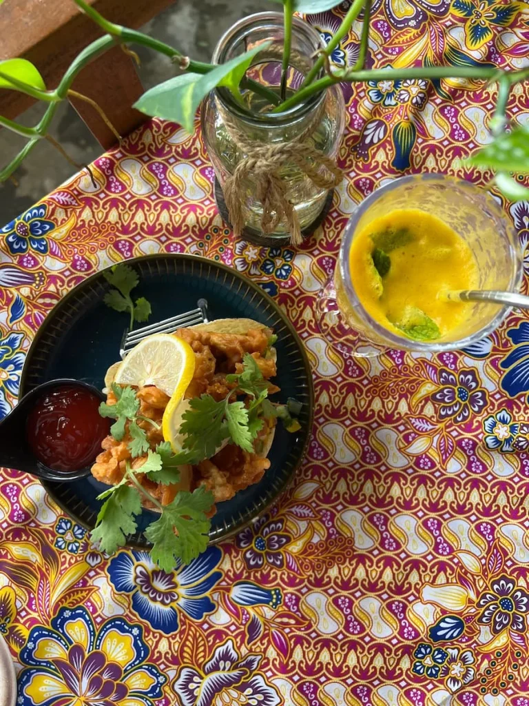 Vegan and Vegetarian food in Langkawi: top lay of Fresh juice and mushroom tacos on table with colourful table cloth underneath.