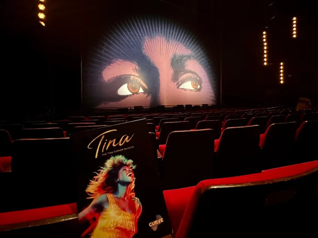Tina the Musical Stage and program in Curve Theatre, Leicester before a performance with the red auditorium seating