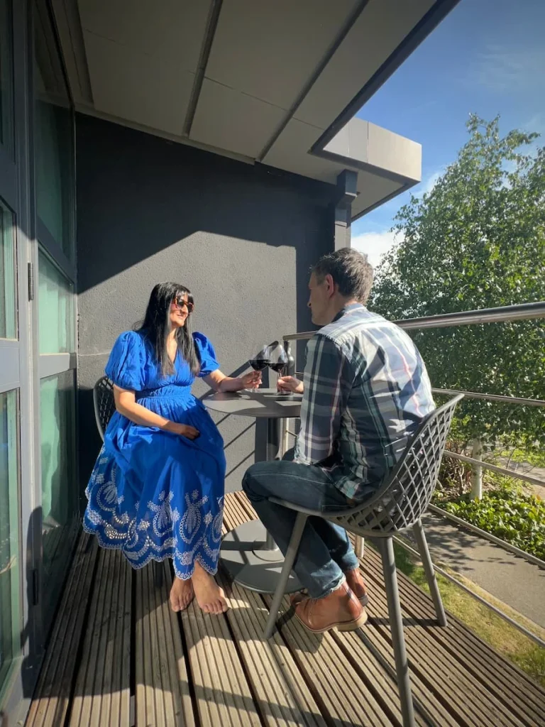 Bejal and Dr C sitting drinking wine on the balcony of the Chancellor's Suite at Burleigh Court Hotel, Loughborough