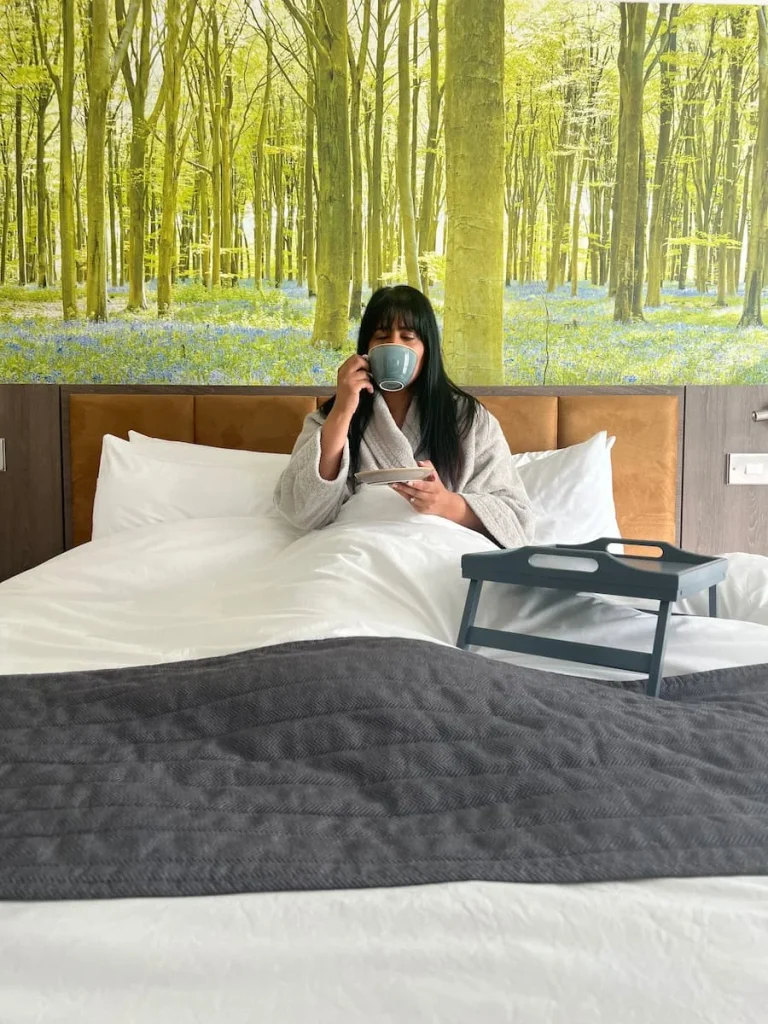 Bejal sipping on a coffee in bed in the Chancellor's Suite at Burleigh Court Hotel, Loughborough
