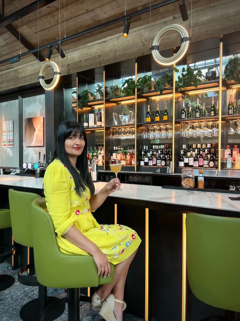 Bejal sitiing at the bar in a lime dress with 'when Tom met Marg' cocktail in hand at Fifty The Street, Loughborough