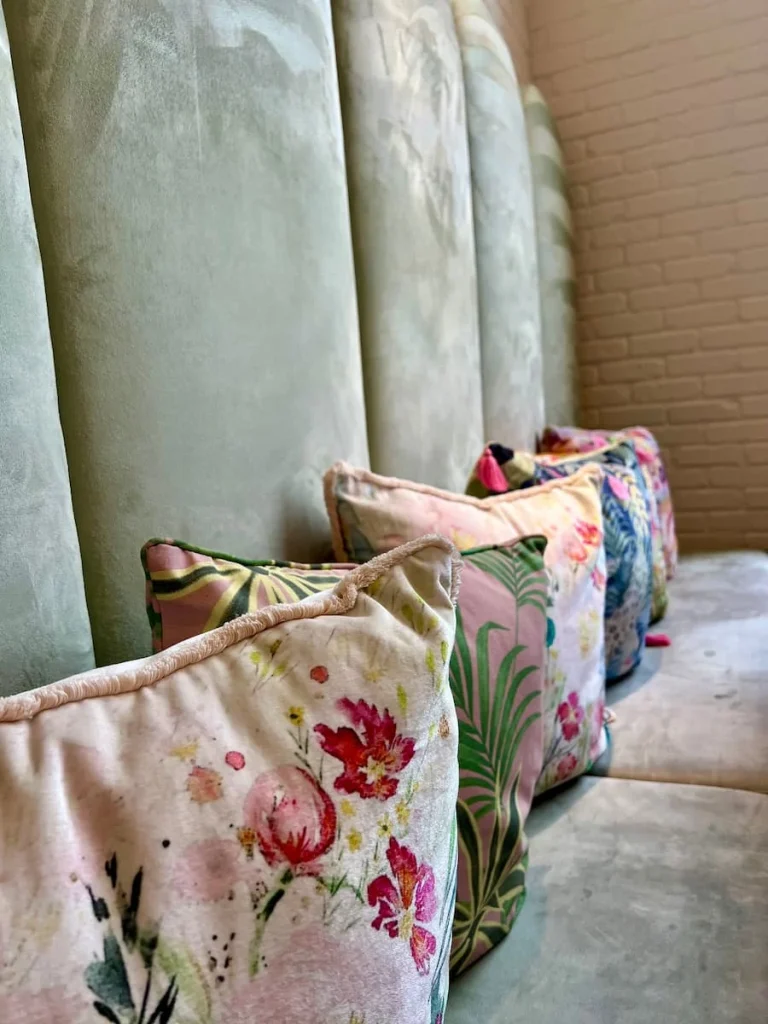 Floral cushions at Sugary, Chicago. They velow cushions are placed against the back of a pastel green velour-effect sofa