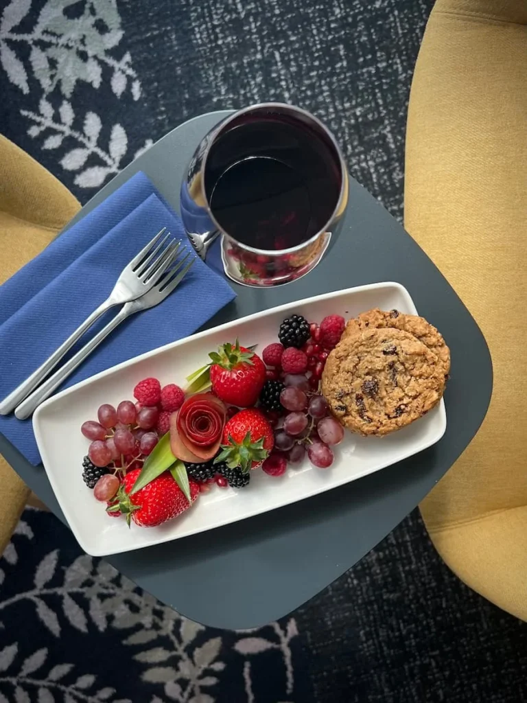 Plate of red fruit and cookies plus a glass of red wine on a table in the Chancellor's Suite at Burleigh Court Hotel, Loughborough