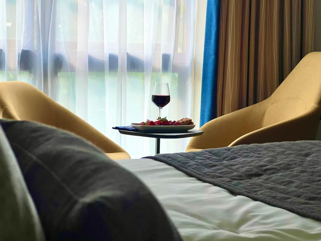 View of table with a wine glass and fruit from the bed at Burleigh Court Hotel, Loughborough