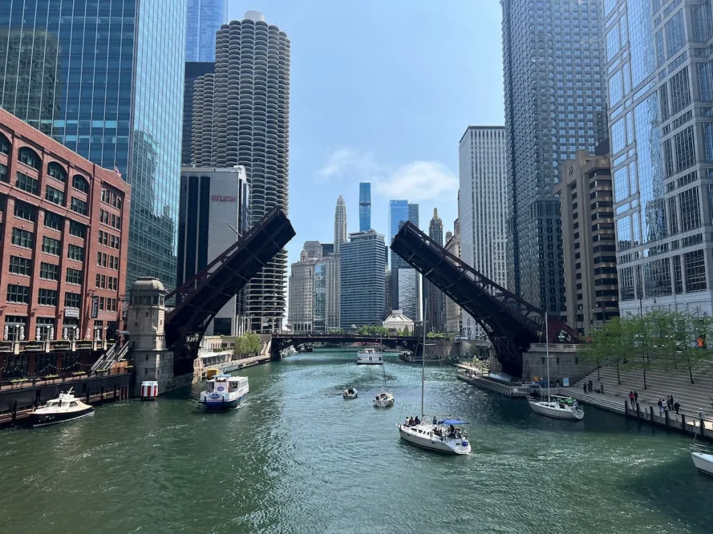 The Riverwalk, Chicago with Clark Street bridge opening up and little boats going through on a sunny day. 