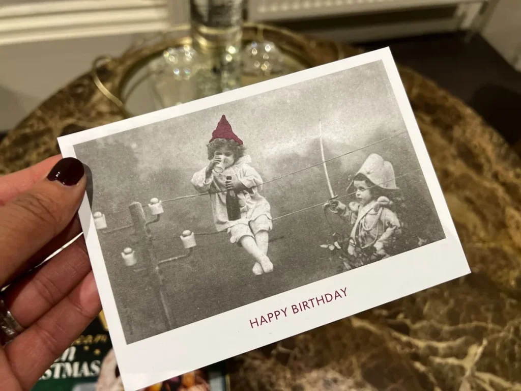 A black and white birthday card for Bejal at the Queensberry Hotel in Bath. The image is of 2 girls one drinking wne with a red hat on!