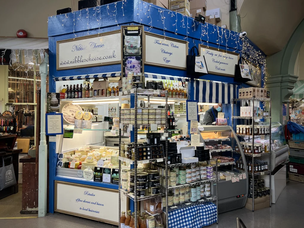 Nibbles cheese stall with a blue exterior and lots of cheese on display at the Bath Guildhall Market