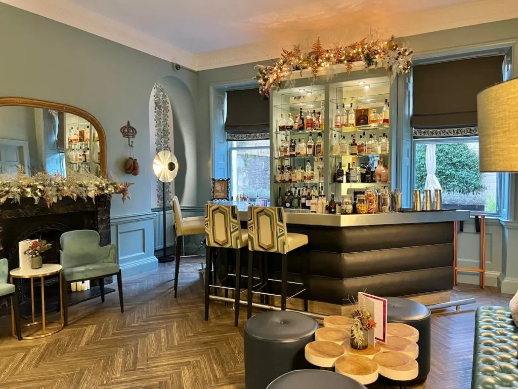 The Queensberry Hotel, Bath  lounges with cool lights and big sofa chairs adn dark wood table for relaxing in. There are two big lights at either end of the room on tall stands