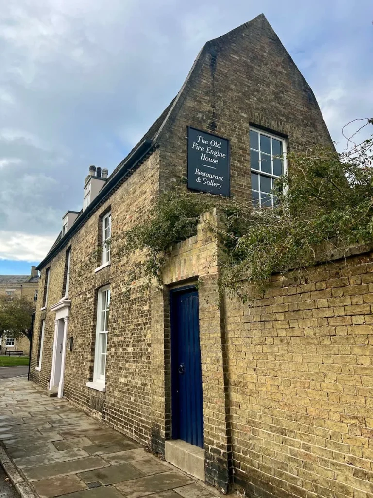 Back view of the Old Fire Engine House with the sign and the black back door. The property has a light brick exterior