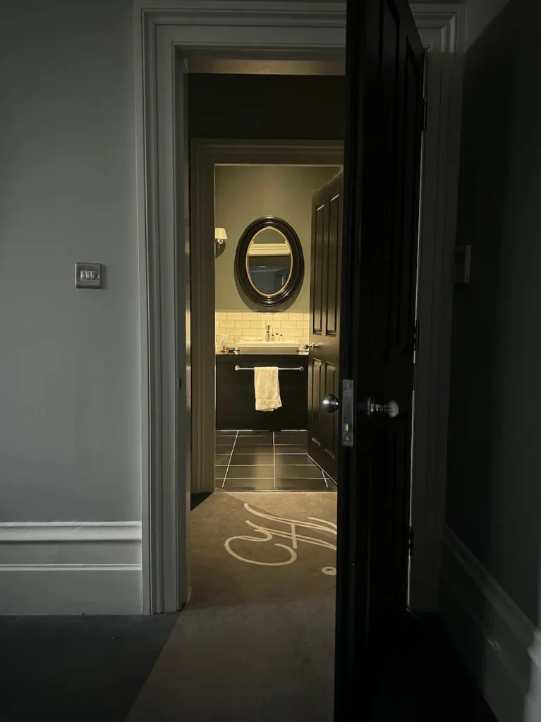 Bathroom at night with sink and toiletteries. Image taken from bedroom suite at Poet's House Hotel, Ely