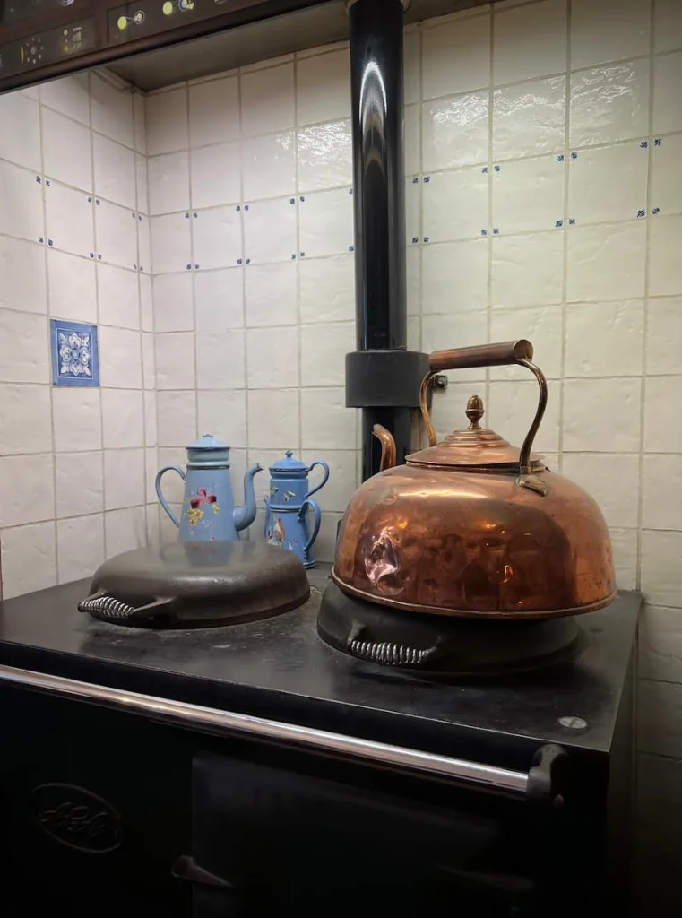 A copper kettle on a range at Peacocks Tearooms in Ely. There is also a light blue coffee pot in the background