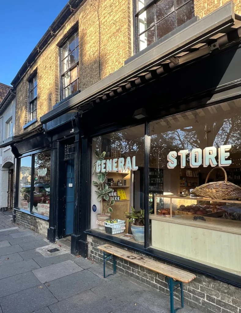 Exterior of the at Bake Shop General Store in Ely. It has a black double-face outside with Bake Shop General Store written in white letters with a yellow shadow.