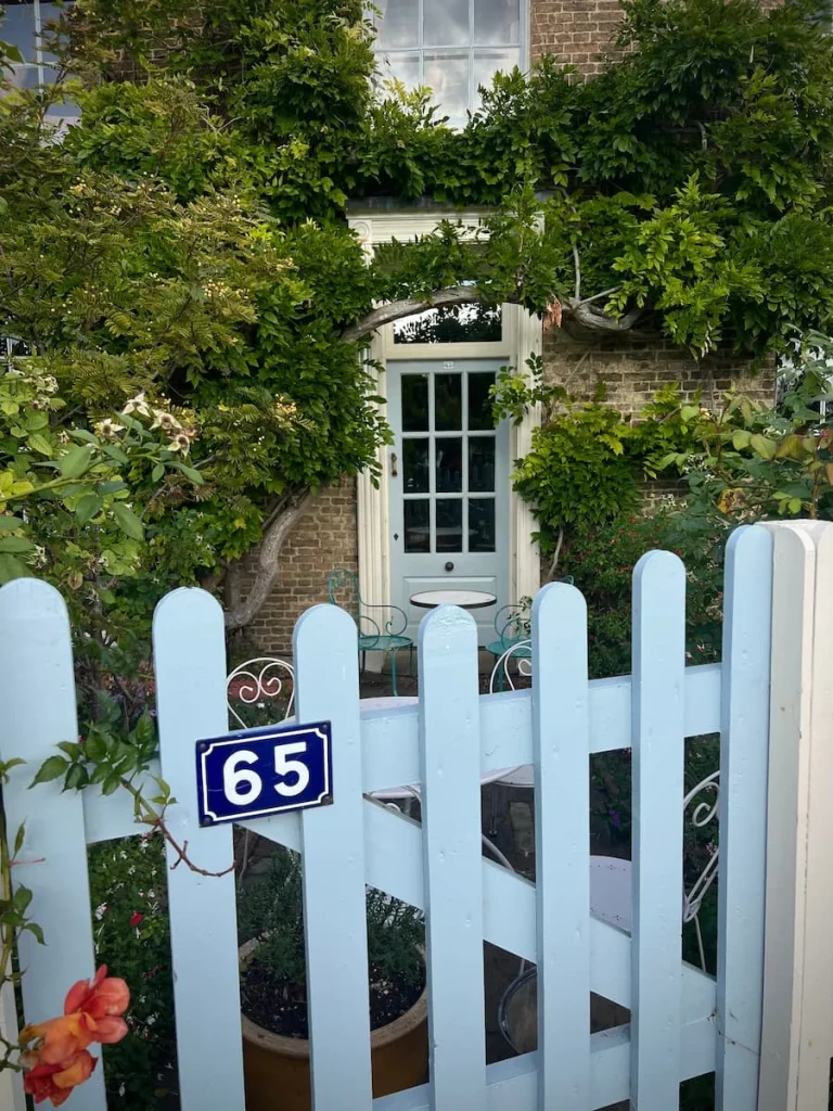 Blue Gate and white window covered with green foliage at Peacocks Tearooms, Ely