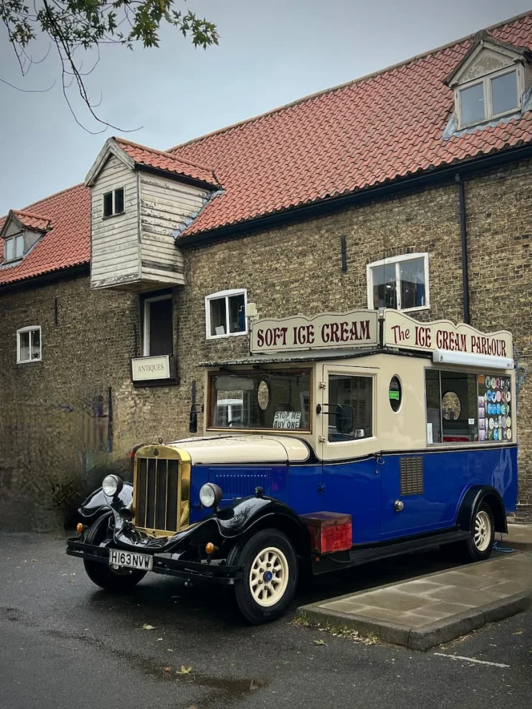 A vintage ice-cream car that navy blue and half cream with red lettering parked outside Waterside Antiques in Ely