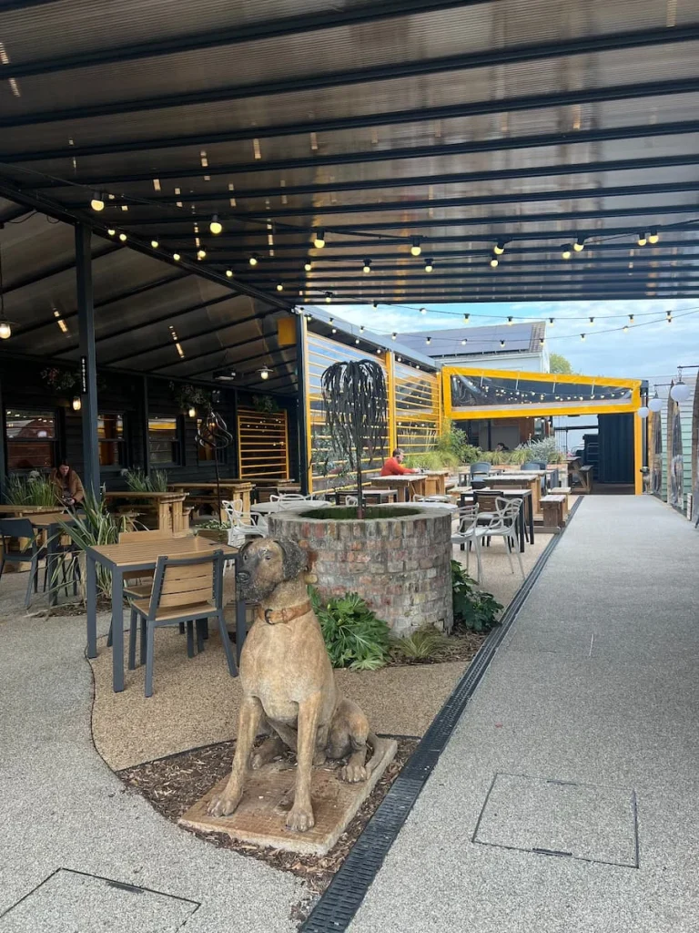 The Yard outdoor seating area with Silver Oak coffee counter, Ely. There are lots of tables and high stools and seats available. The ceiling is covered with fairy lights