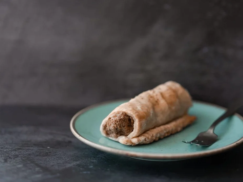 Vegan roll with a small fork on a duck egg blue plate on a dark grey background and surface at Prosper Cafe Ely