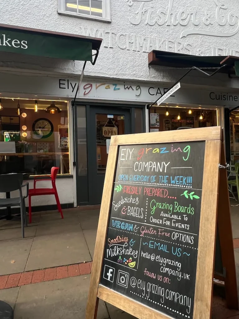 Sandwich board with menu outside Ely Grazing Company. the board is black and with menu items and specials written in pink, yellow, blue and green