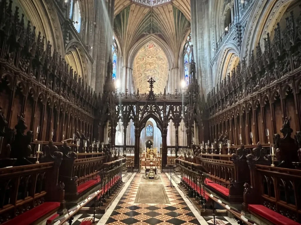 The Choir at Ely Cathedral with the checked black and gold flooring and dark wood choir stand and archways in front. A must visit when considering things to do in Ely