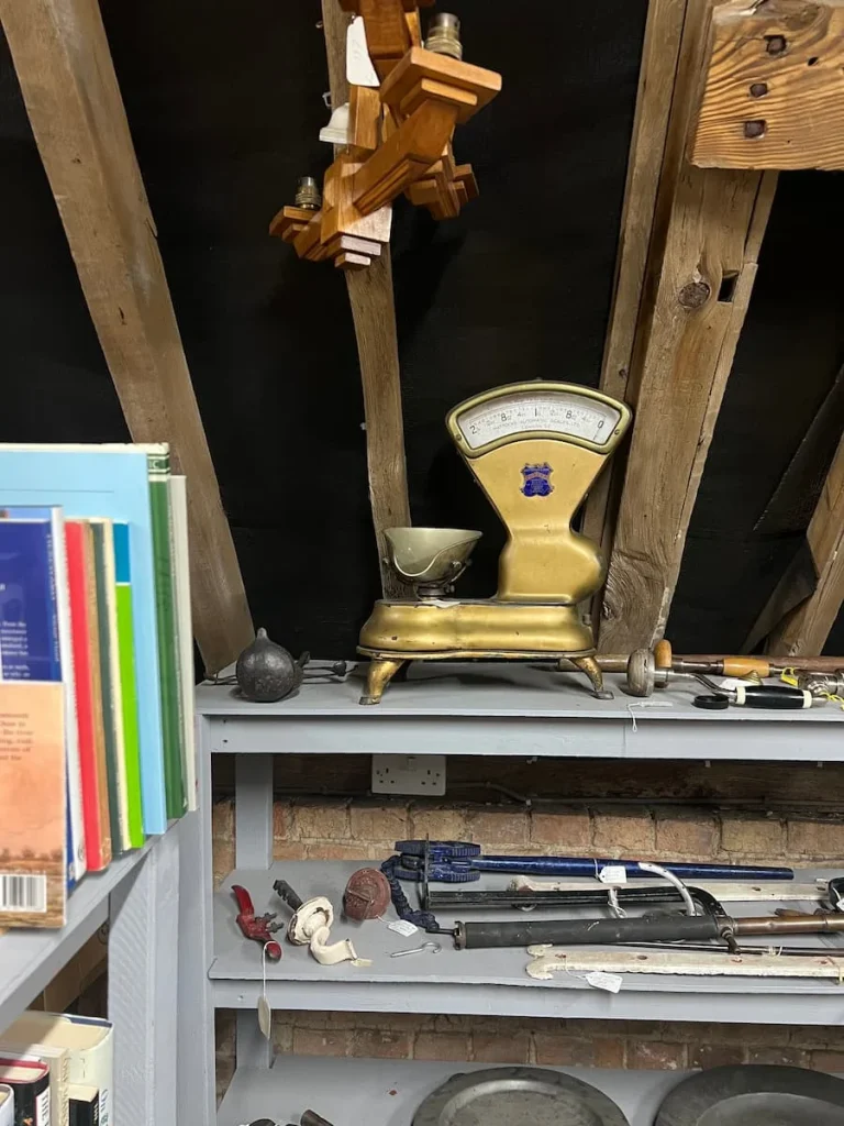 A Vintage yellow scale at Waterside Antiques in Ely. The scales are on a top shelf surrounded by books and other kitchen artefacts