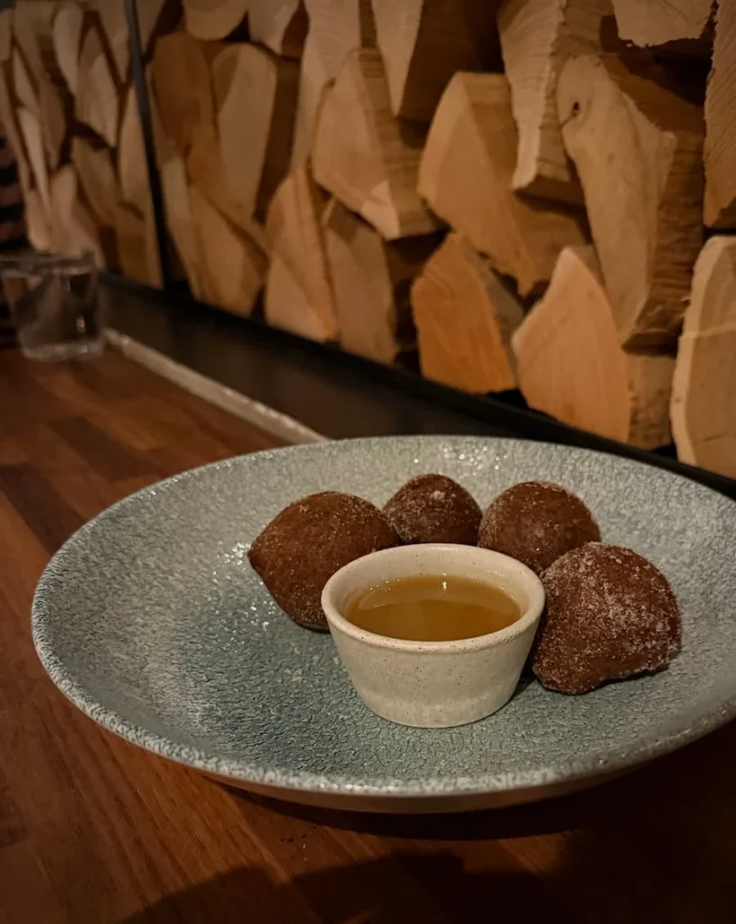 3 circular with butterscotch sauce in a small white bowl at Via Sophia, Washington DC. There are cut wooden logs in the background