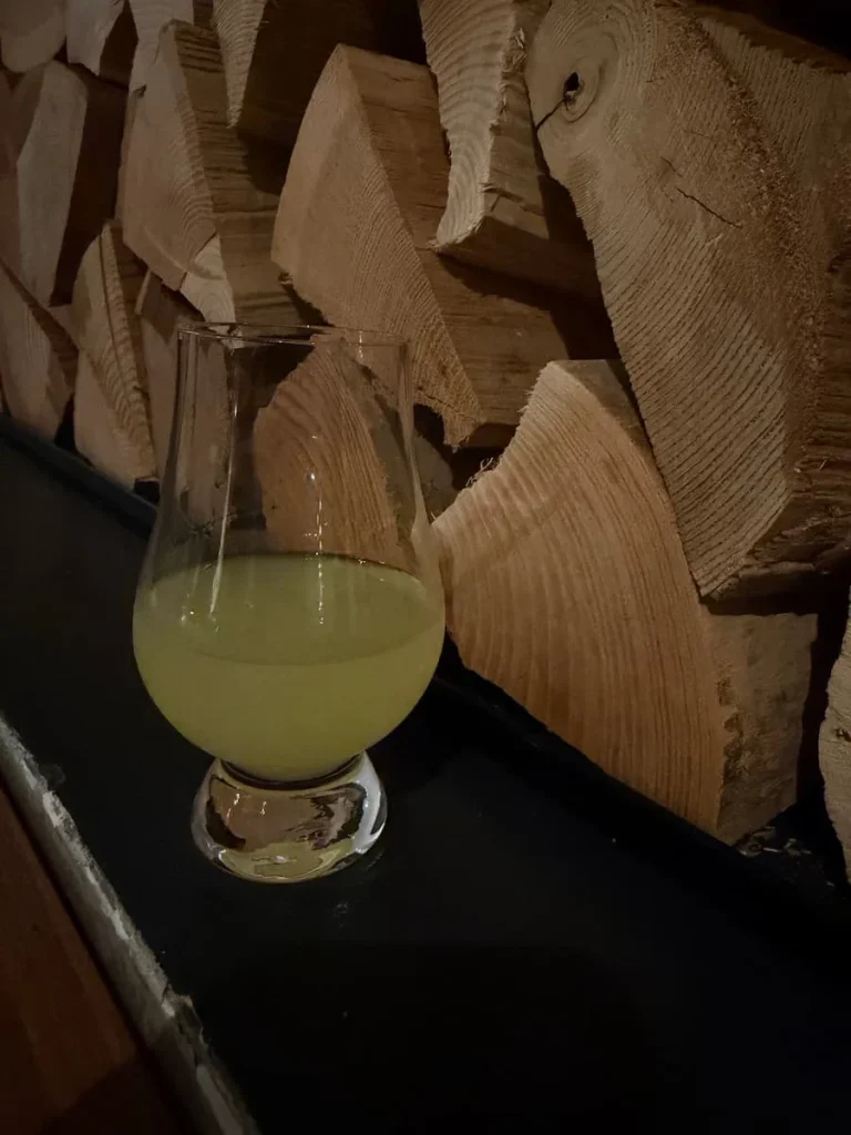 A glass of red wine and bottle of Punzi at Via Sophia, Washington DC. There are cut wooden logs in the background