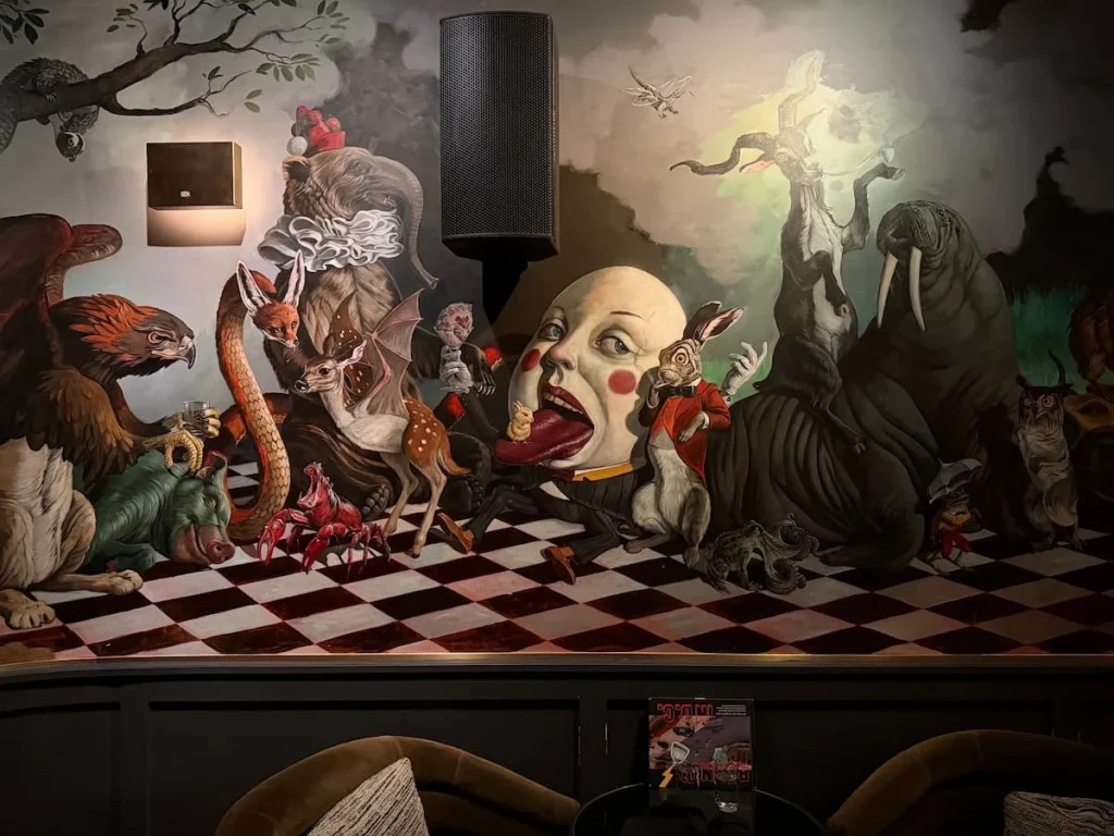 Alice in Wonderland wallpaper at Allegory Washington DC. There is seating underneath the artwork