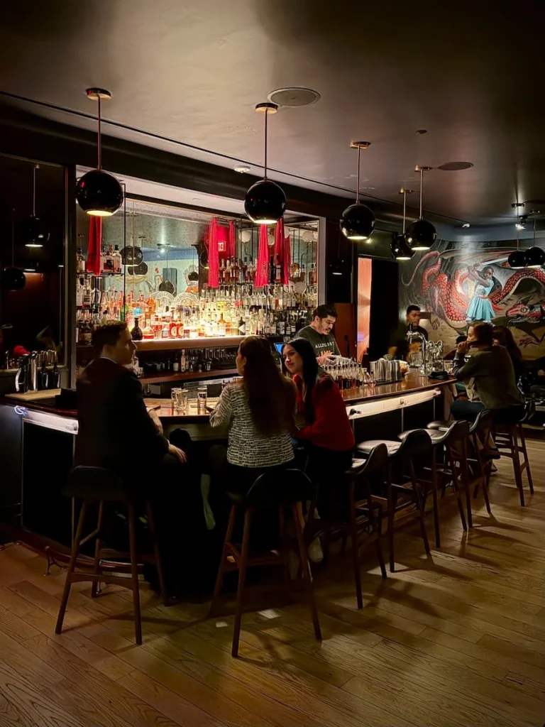 Bar area at Allegory, Washington DC. There are people sitting at the bar chatting and drinking