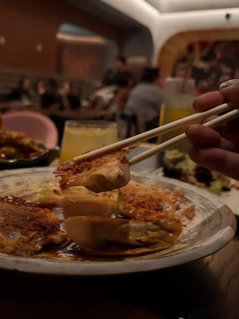 Bejal picking up a crispy Gyoza in a sauce with chopsticks at Planta, Washington DC