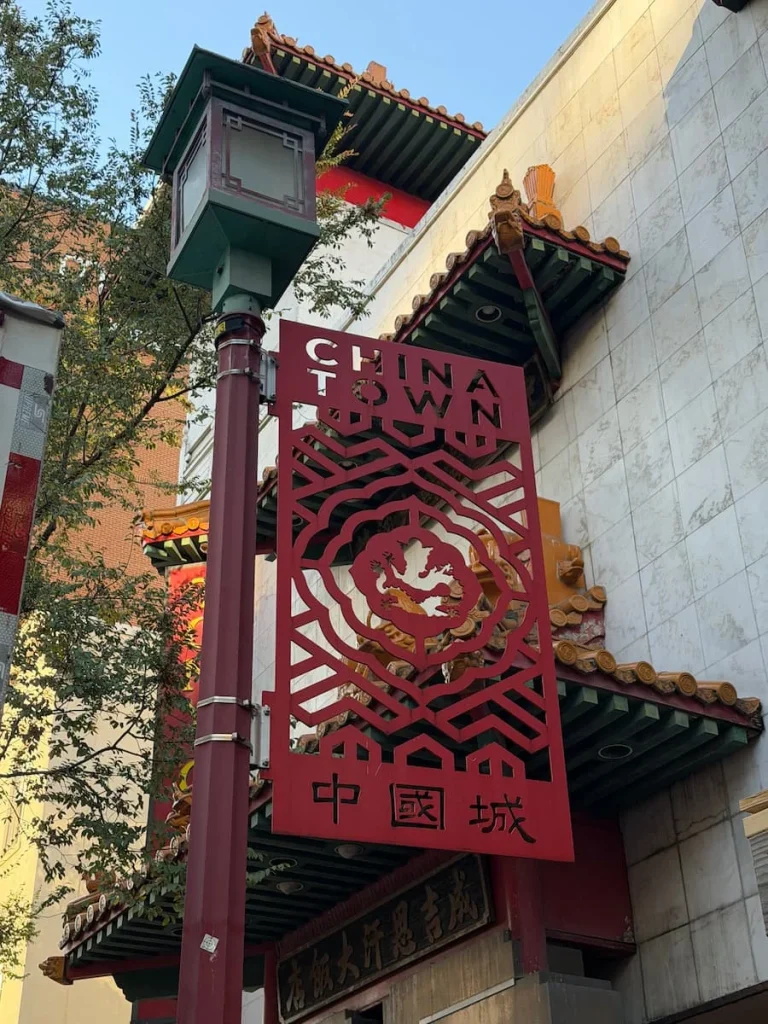 Chinatown sign in Washington DC made from red metal with intricate designs and the chinese-design buildings in the background