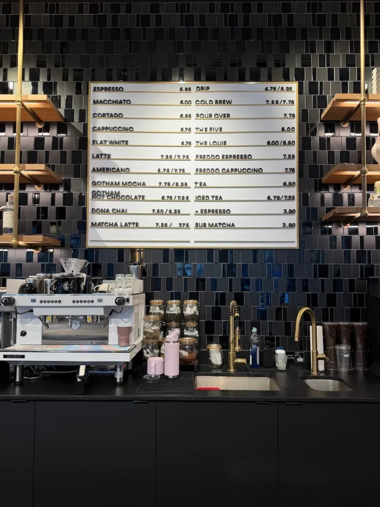 Counter menu at For Five Coffee, Washington DC with a list of the hot drinks available and the syrups and bottled drinks in the background