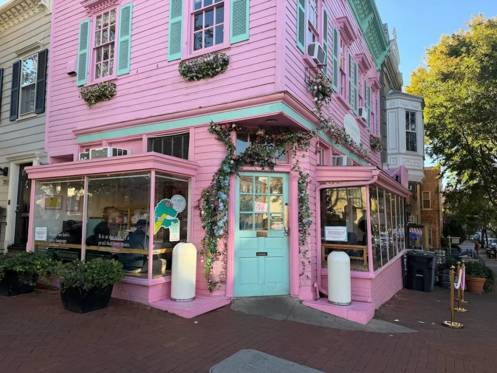 How to spend One day in Georgetown Washington DC. The pink and blue exterior of Call Your Mother, Georgetown, Washington DC. The door is a pastel blue as are the windows of this corner property.