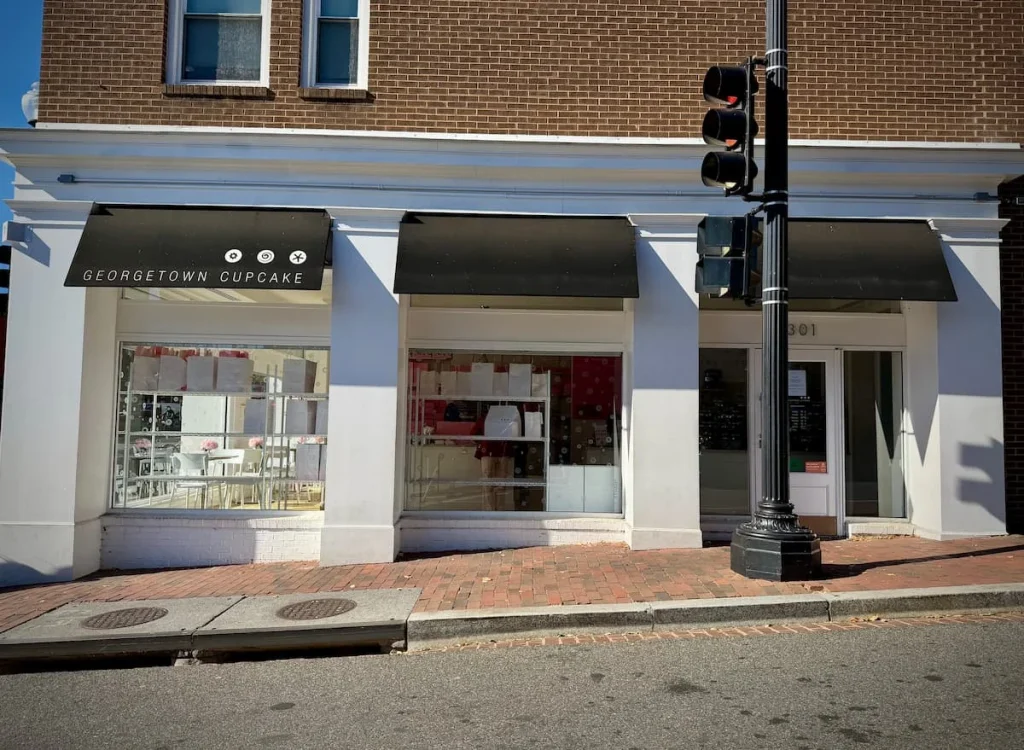 Exterior of Georgetown Cupcakes in a classy white tone with traffic lights right outside the store In Washington DC