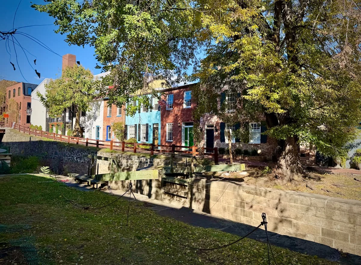 Historic colourful homes along the C&O Canal in Georgetown Washington DC. Pink, blue, yellow historic row houses along the canal with a barge boat in the lock