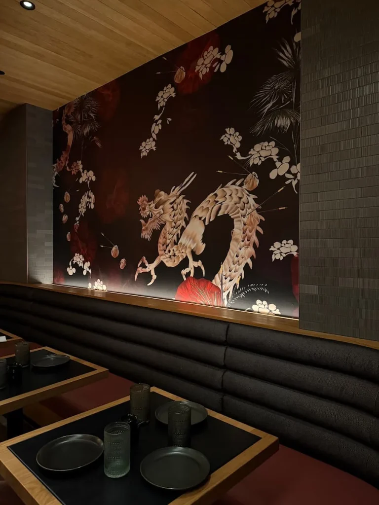 side view of interior dragon wall paper at Planta, Washington DC. The wallpaper as well as the tables with back tops and cutlery at one of the best vegan and vegetarian places to eat in Washington DC