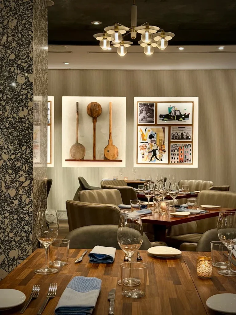 Interiors, wall art, tables and place settings at Via Sophia, Washington DC. The colour scheme is neutral light greys with speckled marble tops