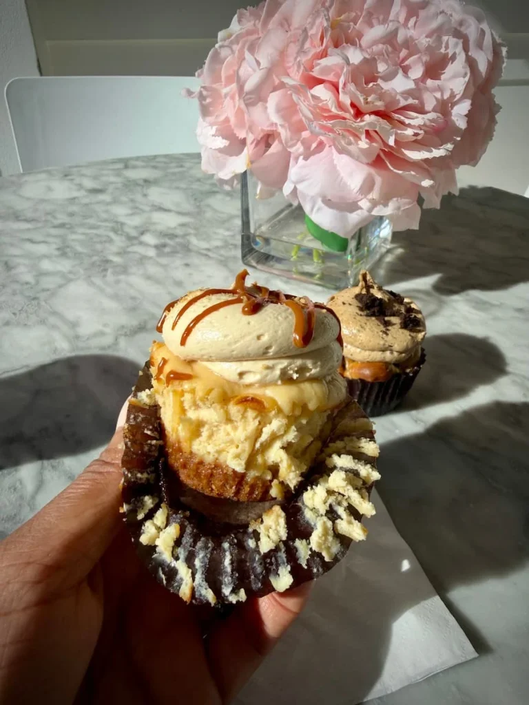 Layers of Apple Pie cupcake filling at Georgetown Cupcakes, Washington DC. Bejal is holding the cupcake and there are pink flowers in a vase in the background