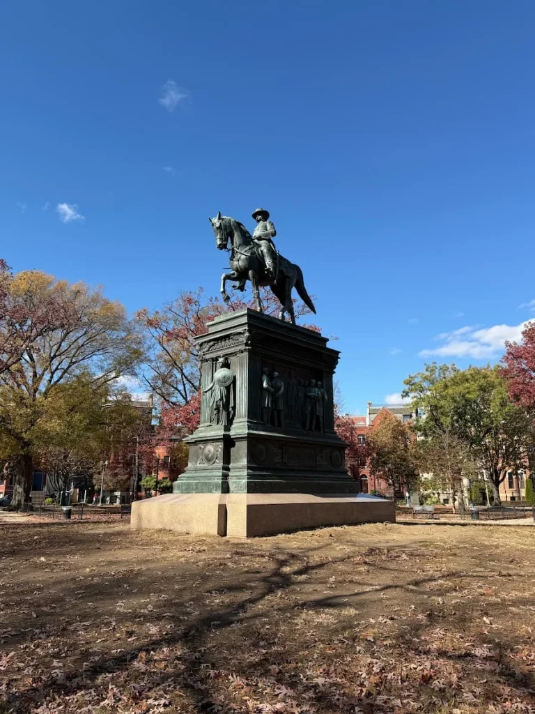 Logan Circle Statue, Washington DC. The circle square is covered with autumnal trees and foliage around teh statue. Logan Circle has a few sustainable hotels in Washington DC