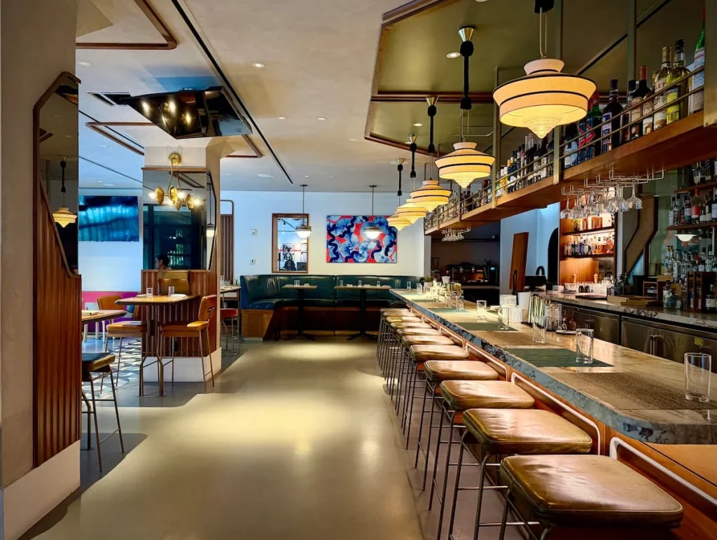 Michele's restaurant from the entrance, Washington DC. The bar is to the right and there is seating on the left hand side and straight ahead. The colour scheme is rose gold and salmon pibks.