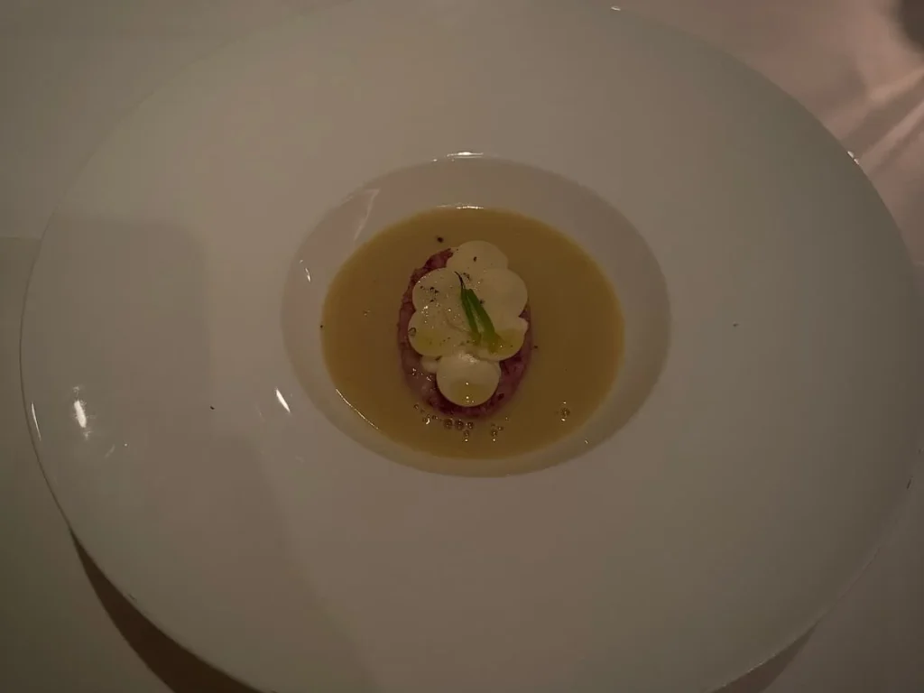 Soup Course at Elizabeths, Washington DC with white dish with white and purple cauliflower and fermented cashew cheese medallions