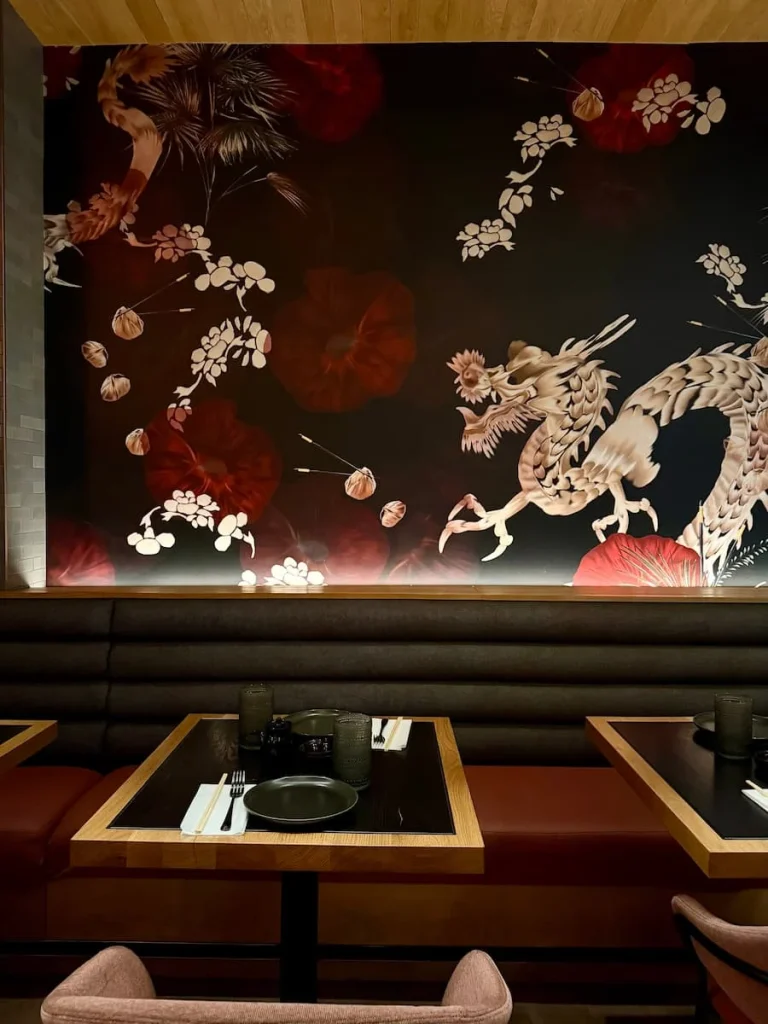 Table settings with pink and cherry coloured dragon wallpaper above black tables with cutlery at Planta, Washington DC