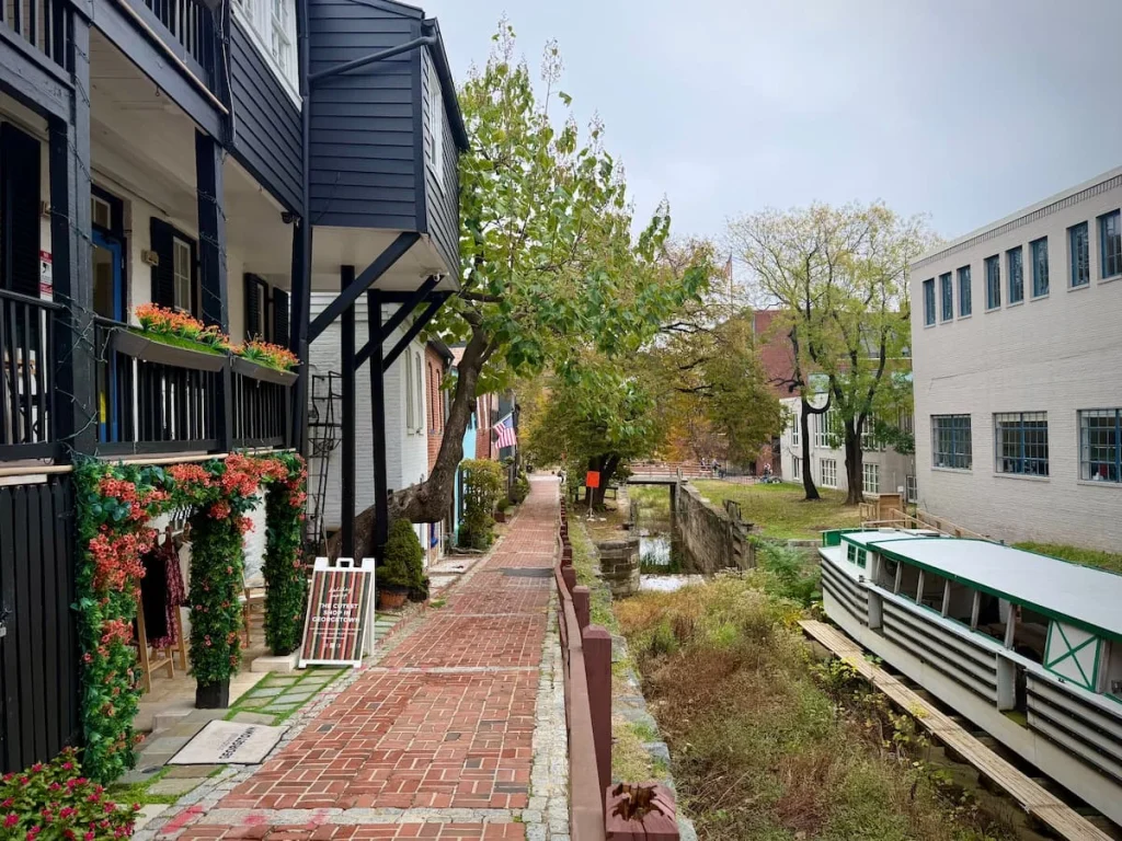 The C&O Canal with old historic houses colourful to the left in Georgetown Washington DC. A barge boat is to the right in the lock