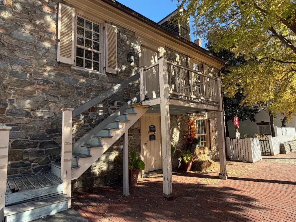 Old Stone House, Georgetown, Washington DC with steps leading upstairs and foliage covering parts of the house's white and cream fascia